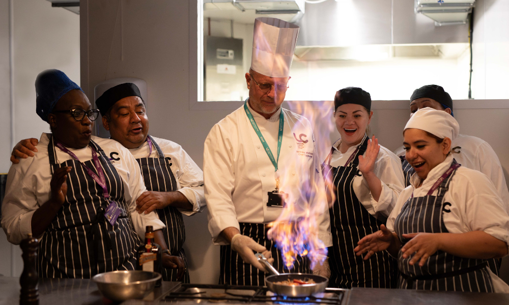 students surrounded by chef as the pan has fire