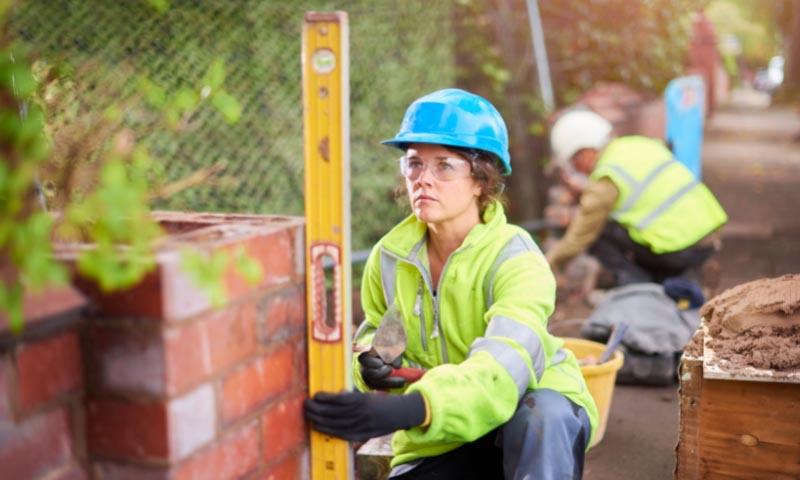 Student checking a brick wall is level