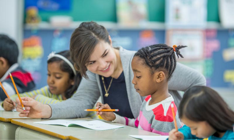 A student teacher assisting young children