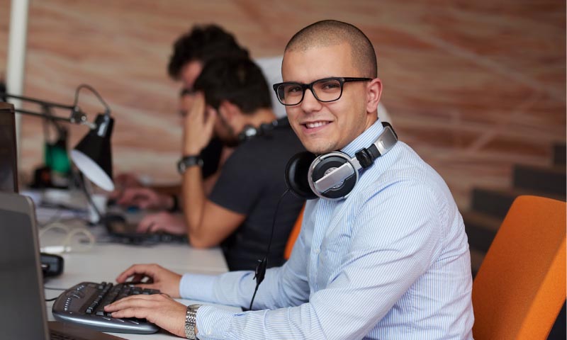 A smiling student sat at a computer workstation